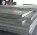 Stacked thick industrial aluminum or stainless steel plates in a warehouse.