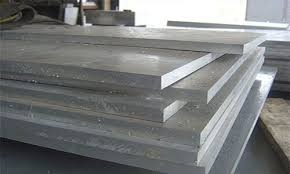 Stacked thick industrial aluminum or stainless steel plates in a warehouse.